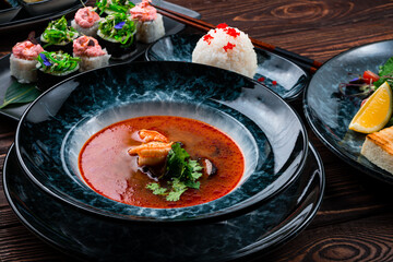 Thai soup Tom yum with mussels, shrimps, herbs and sushi roll set.