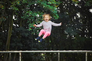 Naklejka premium Child jumping on a trampoline in the evening garden in Denmark