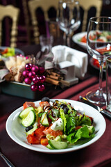 Lunch Greek salad of fresh cucumber, tomato, sweet pepper, lettuce,feta cheese, olives and balsamic vinegar with bruschetta on table.