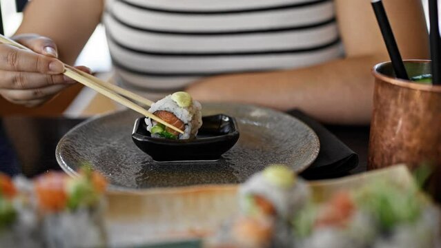 Young beautiful hispanic woman eating sushi at the restaurant