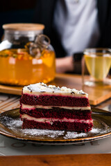 Piece of Red Velvet Cake with sea buckthorn tea with orange, anise in a teapot.