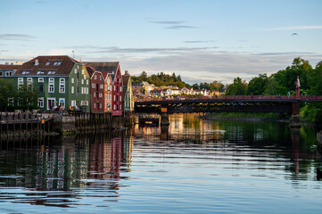Fototapeta na wymiar Fjord with wooden bridge and embankment with colorful wooden houses in Trondheim, Norway.