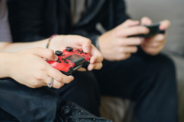 Hands of female teenager pressing buttons on console during video game while sitting in front of computer next to her boyfriend at leisure