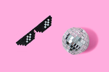 Disco ball and retro glasses on pink background. Flat lay. Party concept.