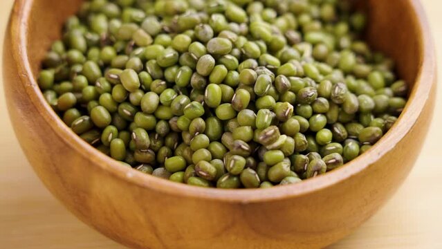 Full wooden kitchen bowl of uncooked mung beans close up. Ecological agriculture. Green soybeans. Rotation