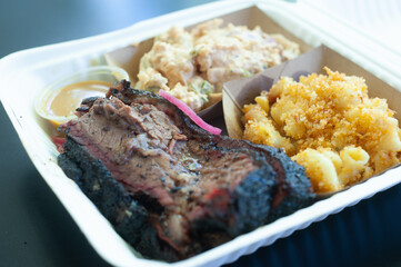 smoked brisket, Mac-n-cheese, potato salad in takeout container