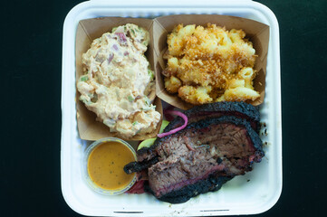 smoked brisket, Mac-n-cheese, potato salad in takeout container