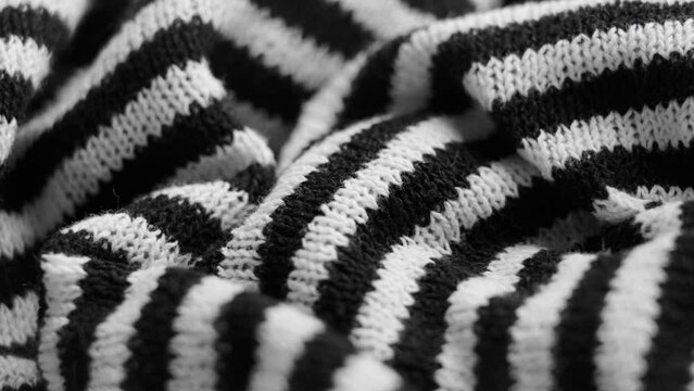 Striped black white knit fashionable material with wrinkles. Abstract crumpled pattern. Macro. Rotation.