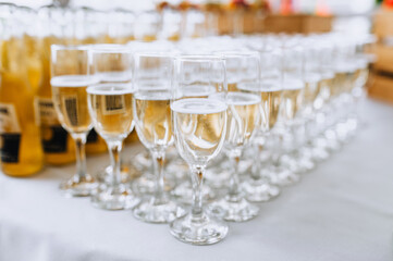 Glass wine glasses with champagne stand on a table in a bar at a banquet. Food photography.