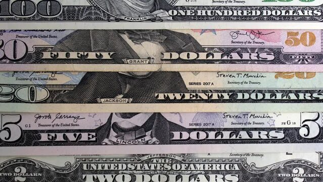 4K video with money background. 1, 2, 5, 20, 50, 100 dollars USA. Set of American paper banknotes of different denominations overlapped. US bill close up. Cash for shopping, debt, loan, tax.  Top view