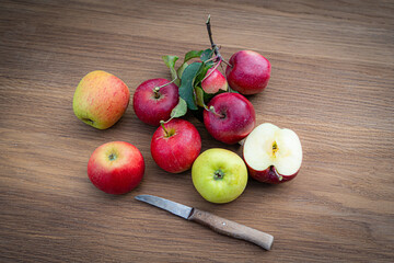 Verschiedene Sorten an Äpfel liegen auf einen Holztisch, ein Apfel ist durch geschnitten.