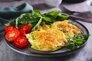 Young cabbage steaks, tomatoes and basil on a plate