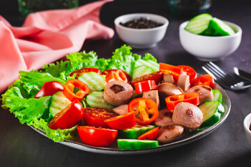 Fried sliced sausages with vegetables and lettuce on a plate