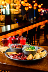 Snacks with cheese, sausages, sun-dried tomatoes, bread sticks, sauce, alcoholic tinctures on the bar counter of the restaurant.