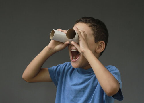 boy looking  through binoculars toilet paper roll on grey background with people stock image stock photo