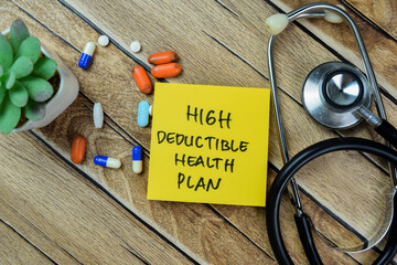 Concept of High Deductible Health Plan write on sticky notes with stethoscope isolated on Wooden...