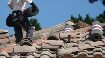 Roofer carrying a roll of underlayment or tarpaper during repair job 
