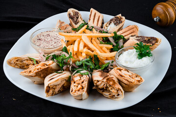 Dinner chicken shawarma with French fries, onions, parsley and sauce.