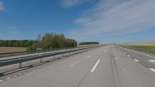 The car drives along the road on a summer day. Highways, roadside and road line markings.