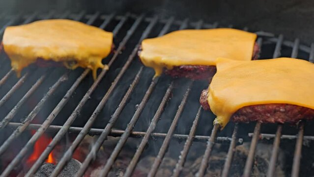 Cheese burgers grilling on a bbq with cheese melting 