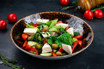 Greek salad of cucumber, tomato, sweet pepper, lettuce, red onion, feta cheese, olives, spices and olive oil.