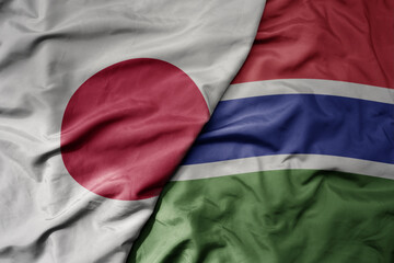 big waving national colorful flag of japan and national flag of gambia .
