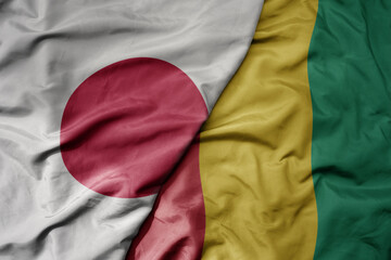 big waving national colorful flag of japan and national flag of guinea .