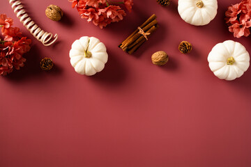 Autumn fall decorations, white pumpkins, walnuts, cinnamon sticks, pine cones on dark red table. Flat lay, top view. Happy Thanksgiving day banner template.