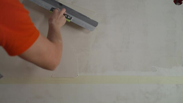 Plasterer applies plaster on the wall during repair and restoration work. Leveling the wall with a spatula. Puttying the wall, leveling with a spatula. The builder levels the putty on the wall with a 