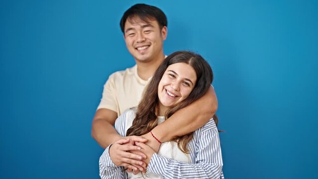 Man and woman couple smiling confident hugging each other over isolated blue background
