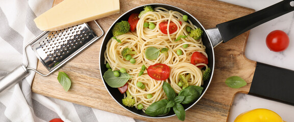 Delicious pasta in frying pan and ingredients on white table, flat lay. Banner design