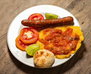 Sausage, patacon and sliced tomatoes, traditional Colombian breakfast