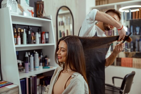 Professional hairdresser holding a comb while cutting hair of woman. Hair care, beauty