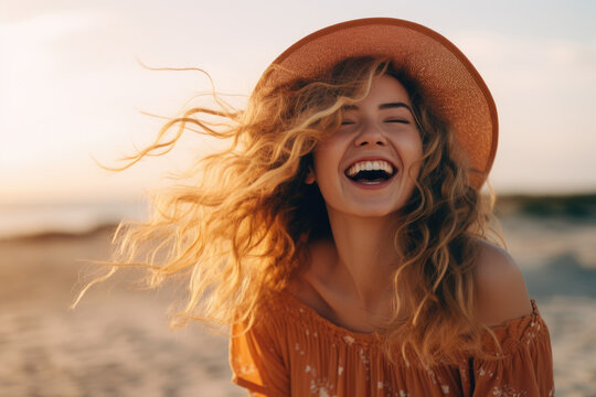 Woman wearing hat is captured laughing on sunny beach. This image can be used to depict joy, relaxation, vacation, or beach-related themes.