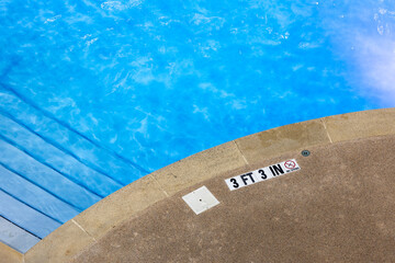 Edge of swimming pool with No Diving warning sign and 3 ft depth marker