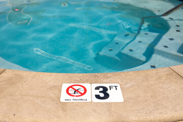 Edge of swimming pool with No Diving warning sign and 3 ft depth marker