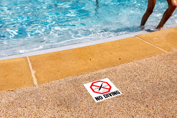 Edge of swimming pool with no diving warning sign.