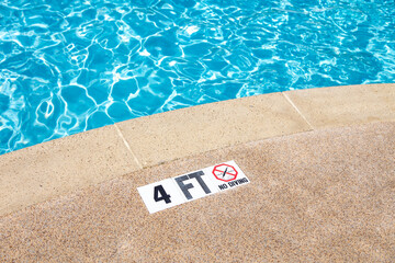 Edge of swimming pool with no diving warning sign and 4 foot depth marker