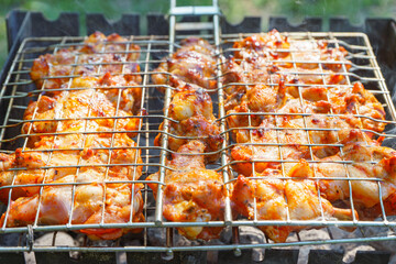 Spicy marinated chicken wings and legs on grill and on a summer barbecue. Cooking process on flame...