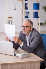 Old male employee working in the office