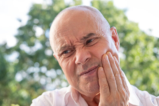 senior, mature man 60-65 years old holds on to jaw, close up male face with facial expression suffering, unbearable tooth pain, toothache, dental pain, oral discomfort, throbbing tooth pain