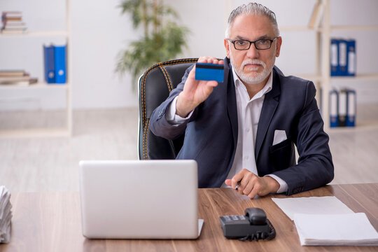 Old male employee holding credit card