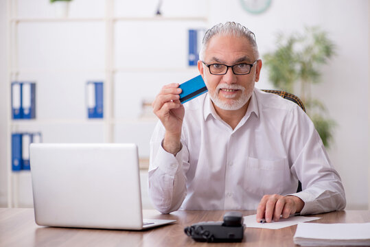 Old male employee holding credit card