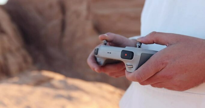 Drone remote control settings screen hands close up with desert background