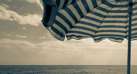vintage beach umbrella by the sea and a cloudy sky