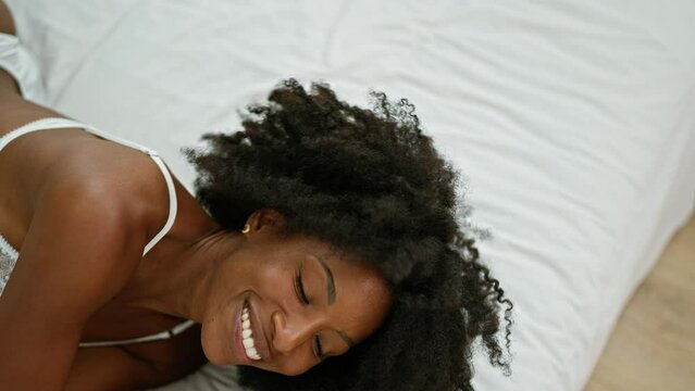 African american woman smiling confident lying on bed looking sexy at bedroom