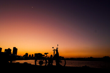 Campos dos Goytacazes, RJ, Brazil, 08/19/2023 - Woman and child with a bike in silhouette at sunset