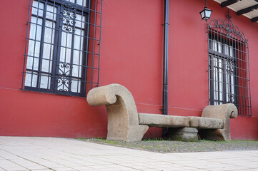 Stone bench in front of Traditional adobe house in the center of a south american small town (Talca, Chile)