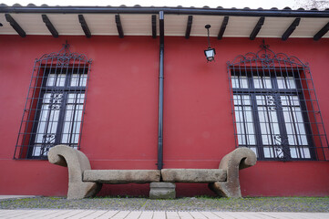 Stone bench and traditional adobe house in the center of a south american small town (Talca, Chile)