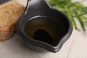 Saucepan of organic balsamic vinegar with oil on light grey table, closeup
